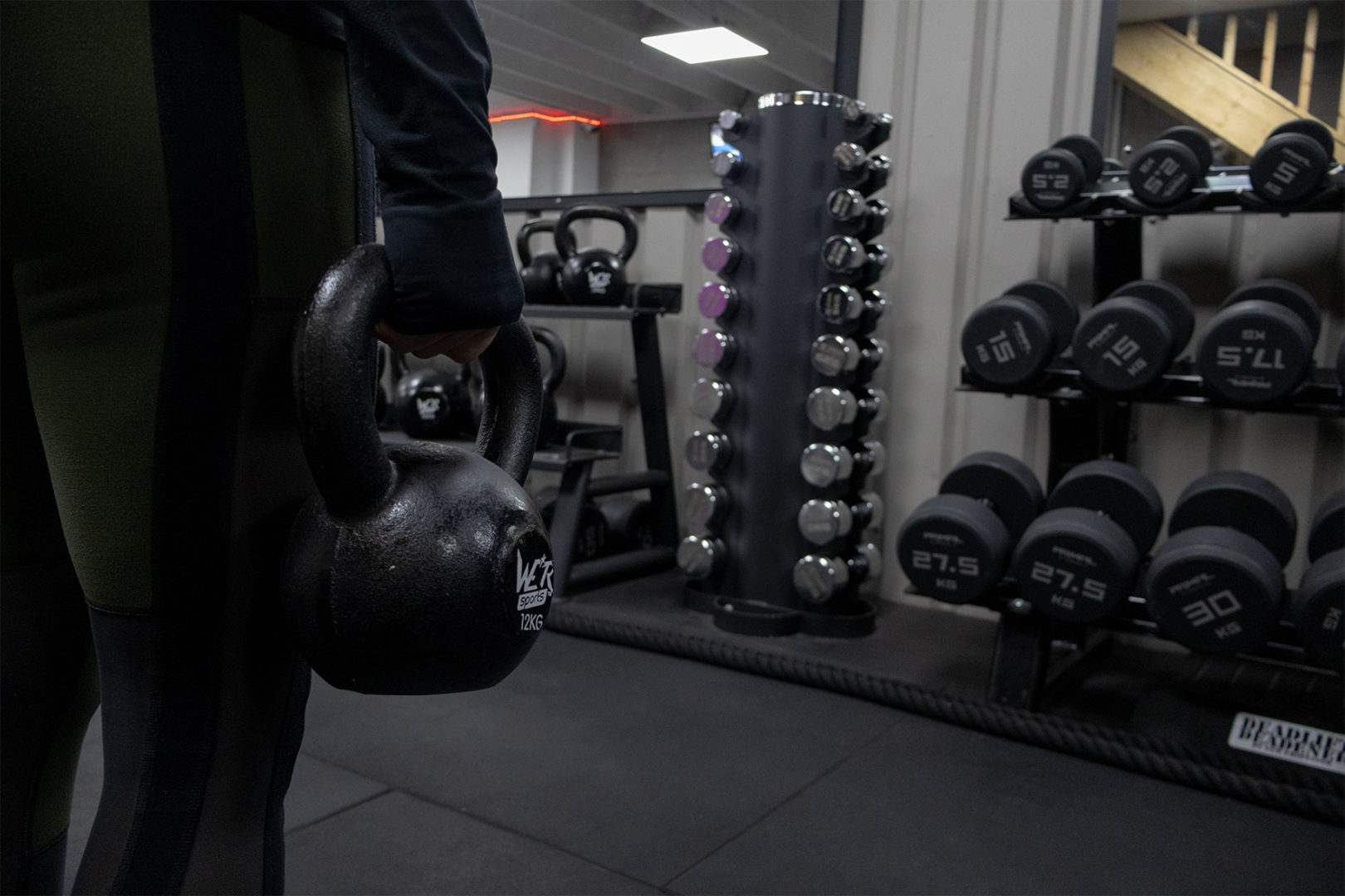 Client facing the wall, close up image of them holding a kettlebell