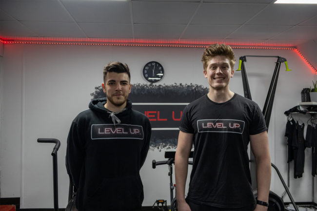 Both coaches standing and smiling at the camera in the main gym space