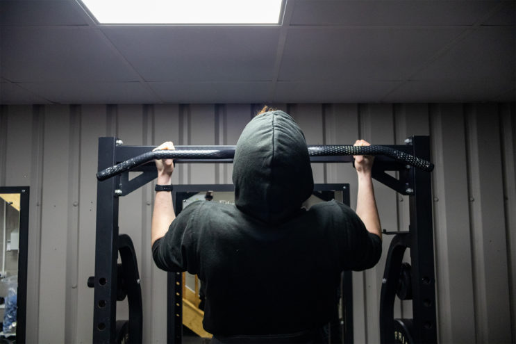 man doing pull ups in gym