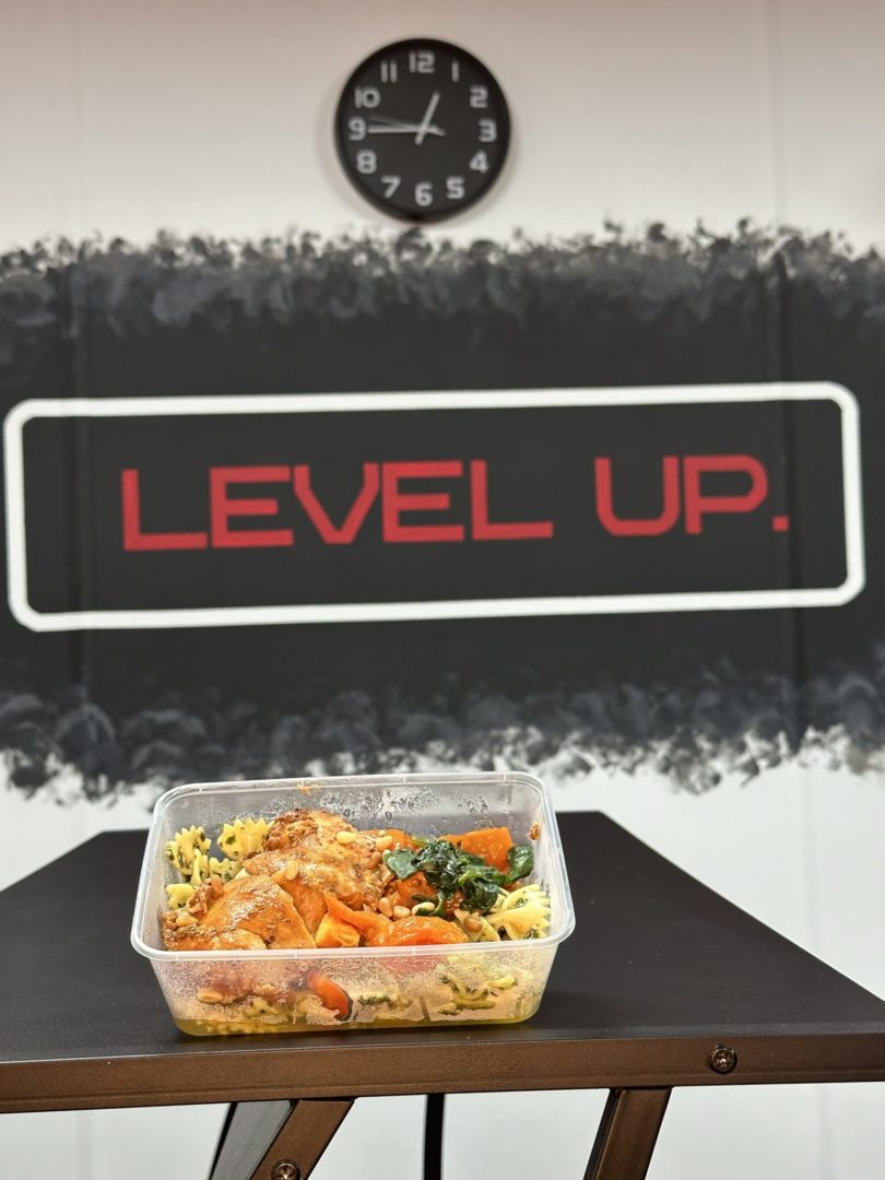 Pesto Pasta Chicken, with the level up logo behind the food